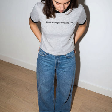 Model wearing the White and Caviar Don't Apologize for Being You cropped ringer tee, front print