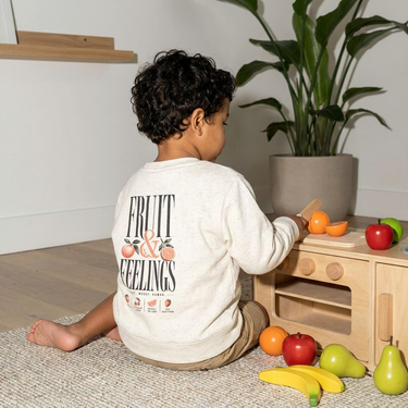 Model wearing the Natural Heather Fruit & Feelings toddler sweatshirt, back print