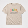 BCBA - Board Certified Behavior Analyst College Style Tee Sand t-shirt, front