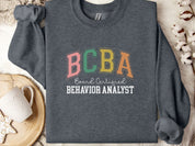 BCBA - Board Certified Behavior Analyst College Style Sweatshirt-Dark Heather-Neurodiversity, ADHD & Autism Awareness & Acceptance Sweatshirt by Daily Bloom