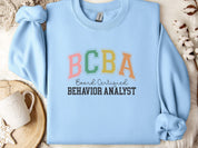 BCBA - Board Certified Behavior Analyst College Style Sweatshirt-Light Blue-Neurodiversity, ADHD & Autism Awareness & Acceptance Sweatshirt by Daily Bloom