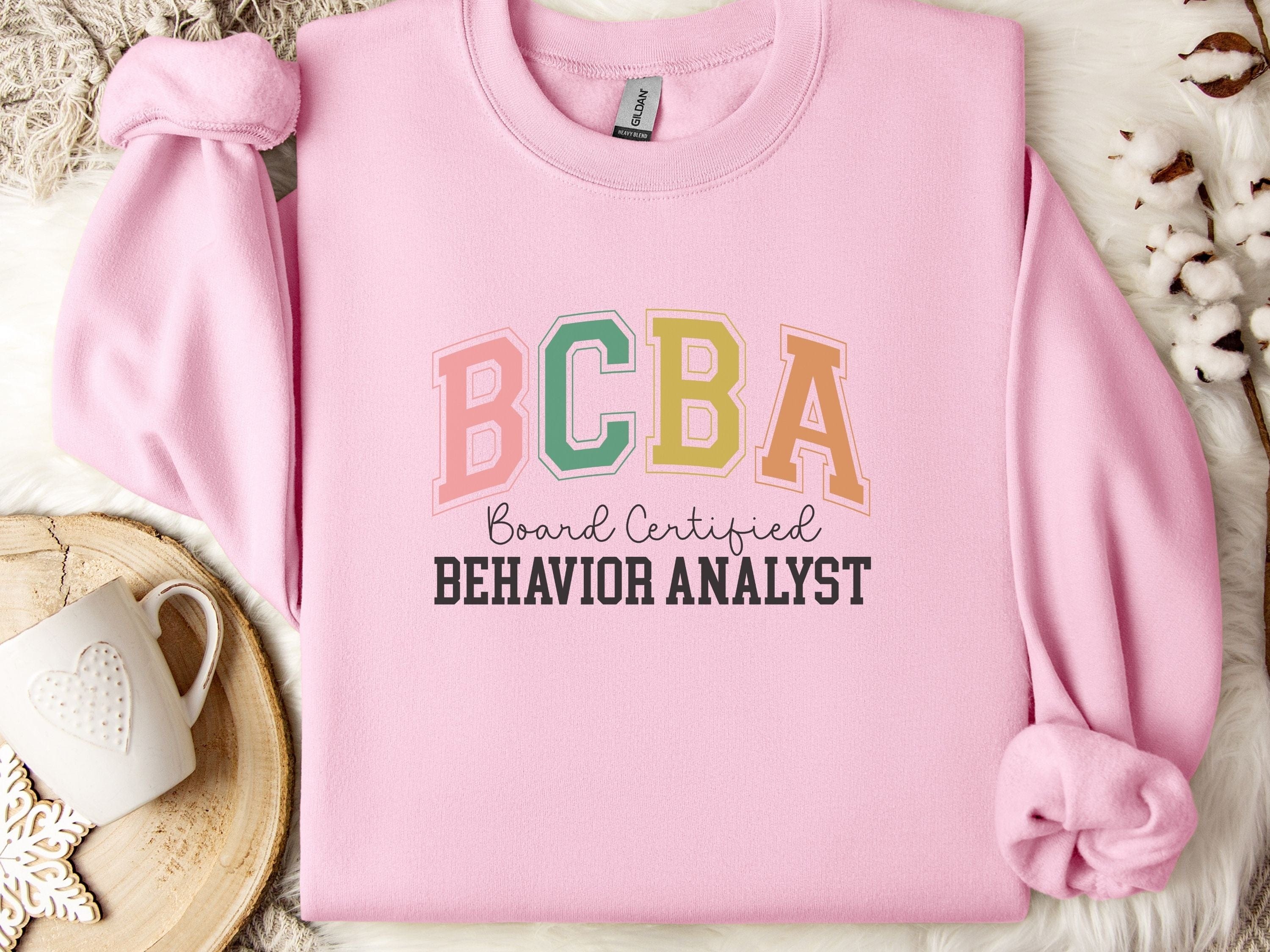 BCBA - Board Certified Behavior Analyst College Style Sweatshirt-Light Pink-Neurodiversity, ADHD & Autism Awareness & Acceptance Sweatshirt by Daily Bloom