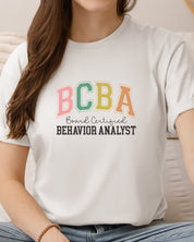 BCBA - Board Certified Behavior Analyst College Style Tee-Neurodiversity, ADHD & Autism Awareness & Acceptance T-Shirt by Daily Bloom